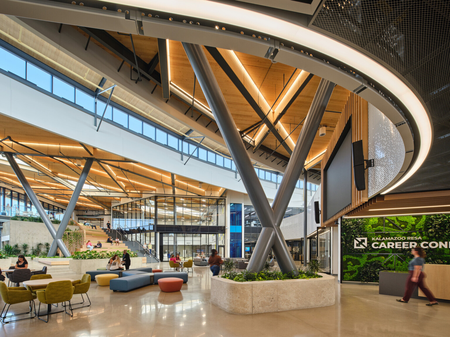 Kalamazoo RESA career technical education central open area featuring exposed wood structure, natural materials, and biophilic design elements; modular community seating