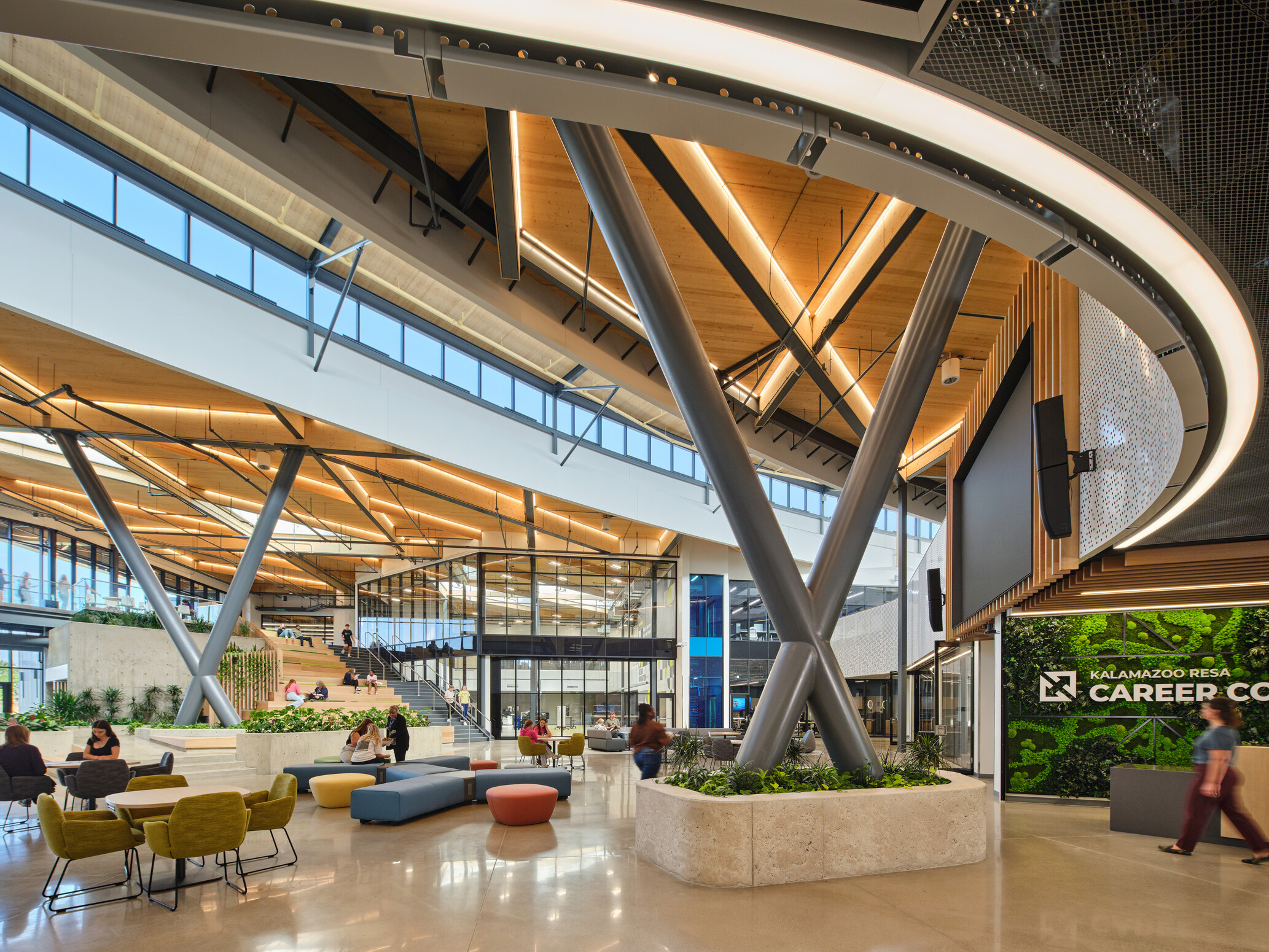Kalamazoo RESA career technical education central open area featuring exposed wood structure, natural materials, and biophilic design elements; modular community seating