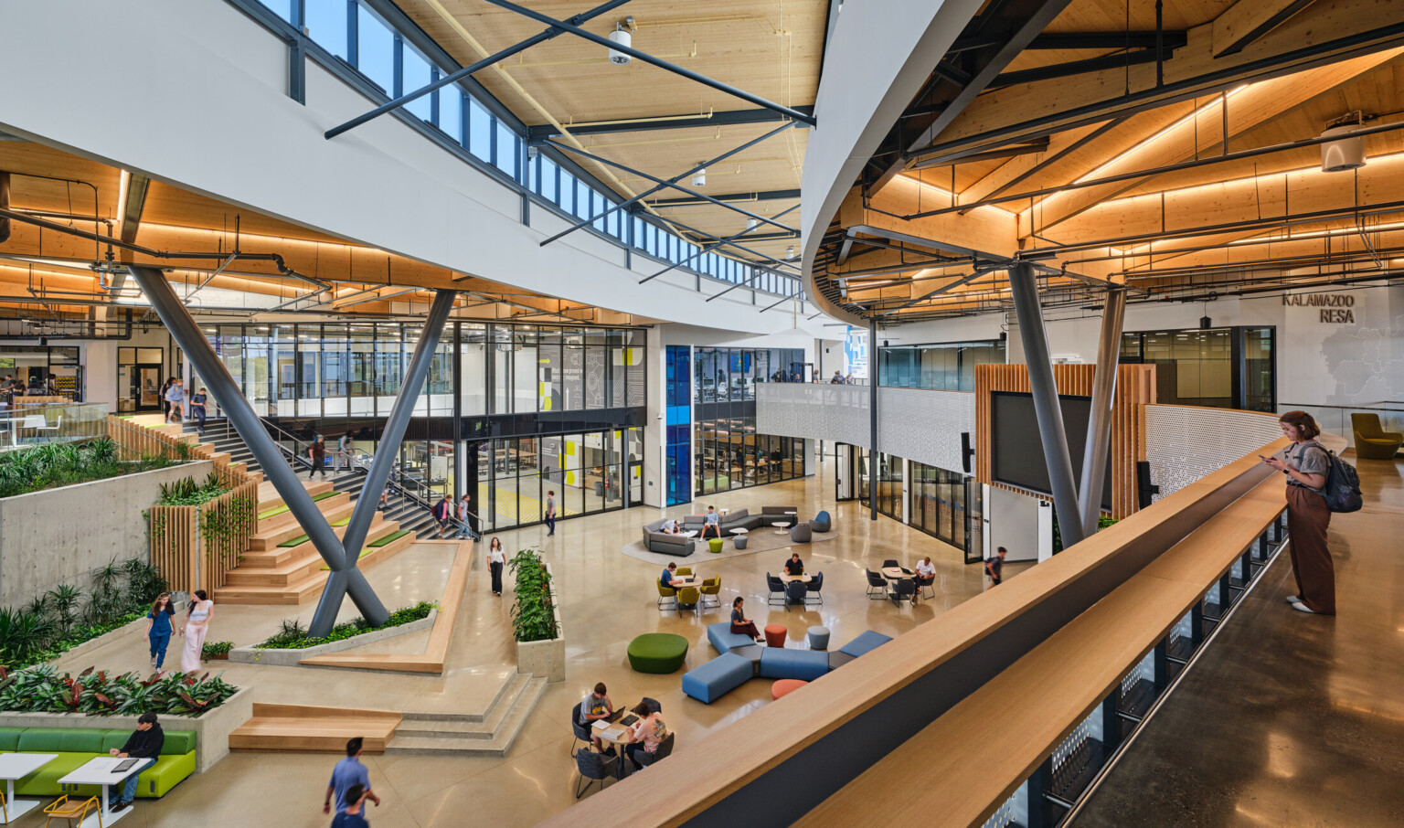 Kalamazoo RESA career technical education central open area featuring exposed wood structure, natural materials, and biophilic design elements; modular community seating