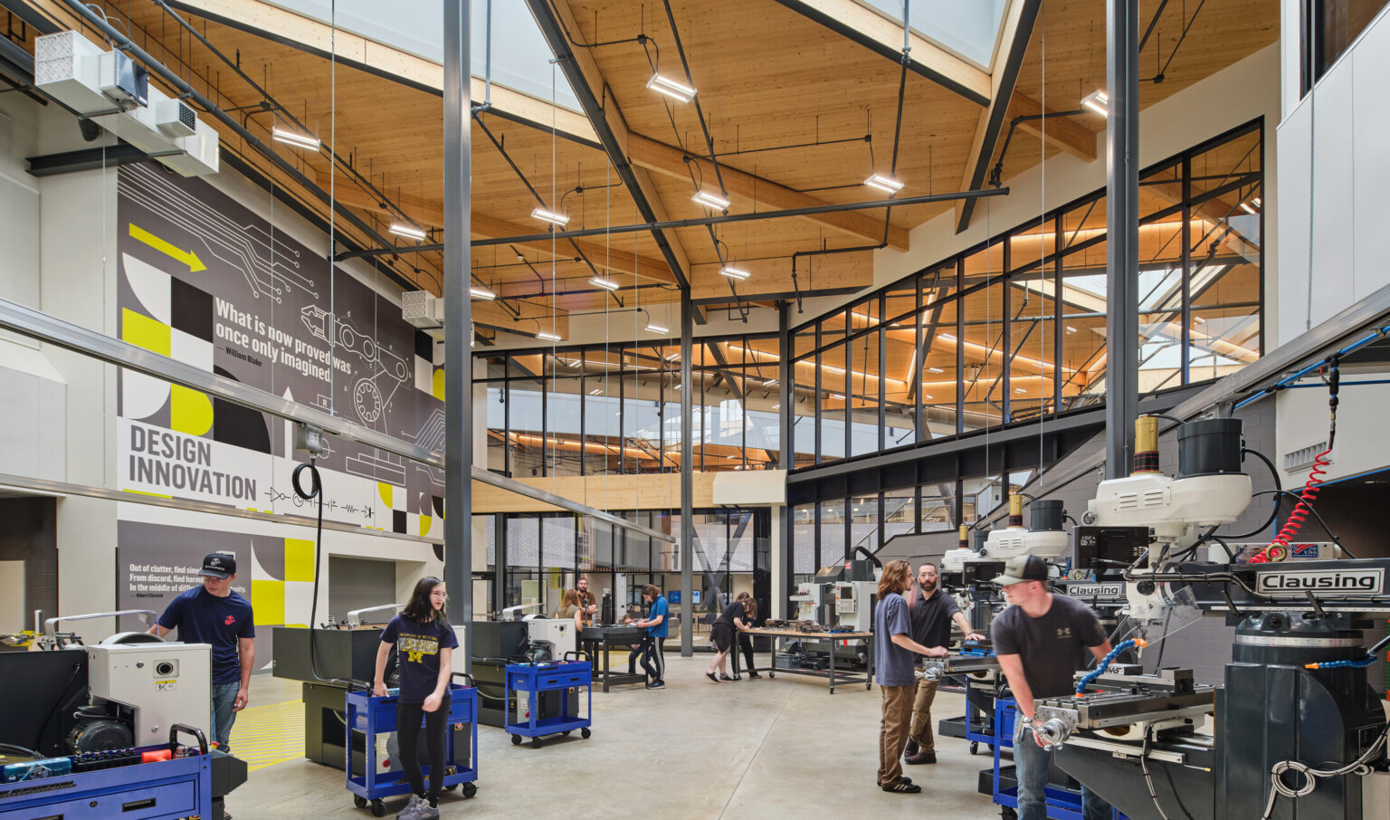 Technical classroom within Kalamazoo RESA career technical education building featuring exposed wood structure, natural materials, and biophilic design elements; students working at stations in a large double heigh space