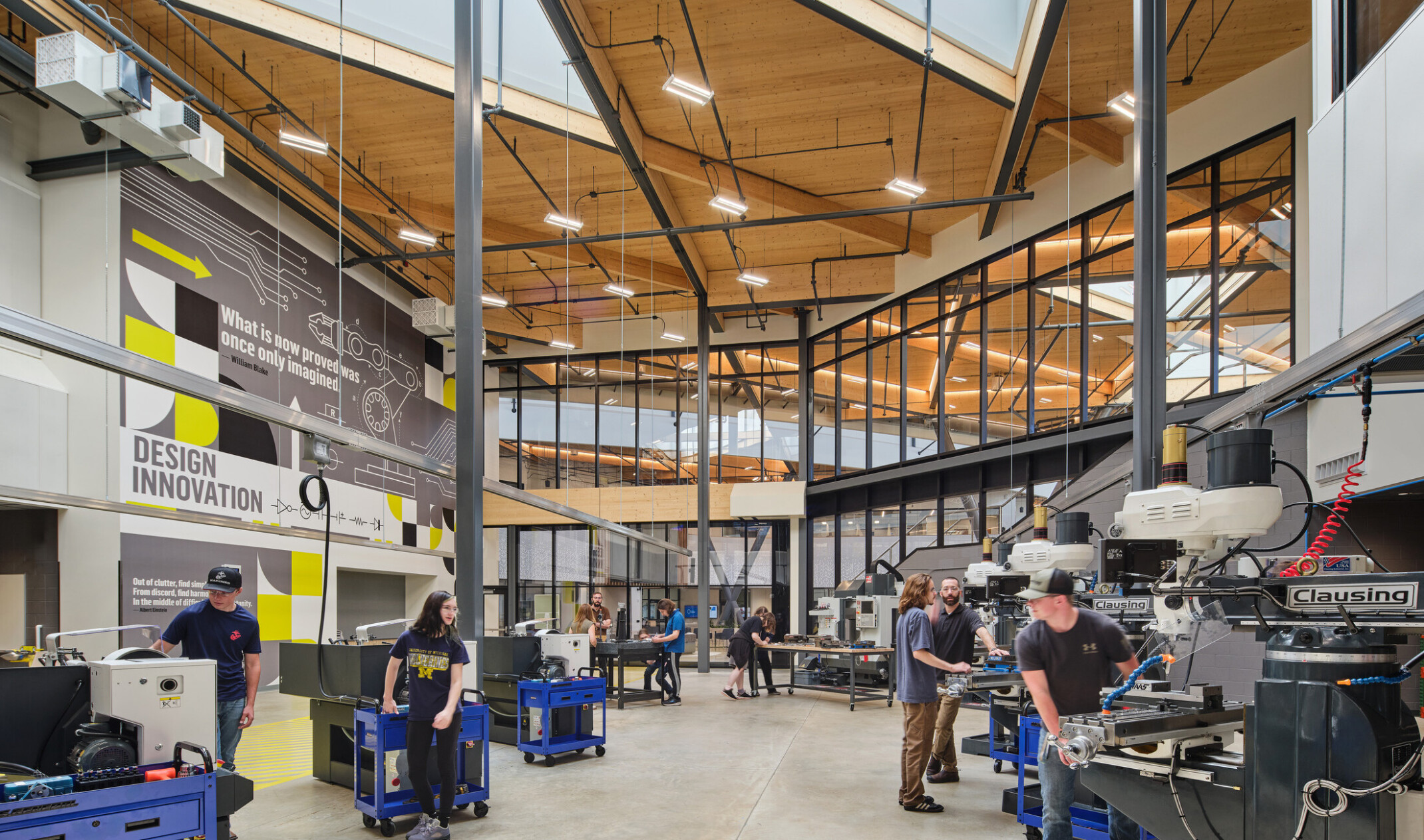 Technical classroom within Kalamazoo RESA career technical education building featuring exposed wood structure, natural materials, and biophilic design elements; students working at stations in a large double heigh space