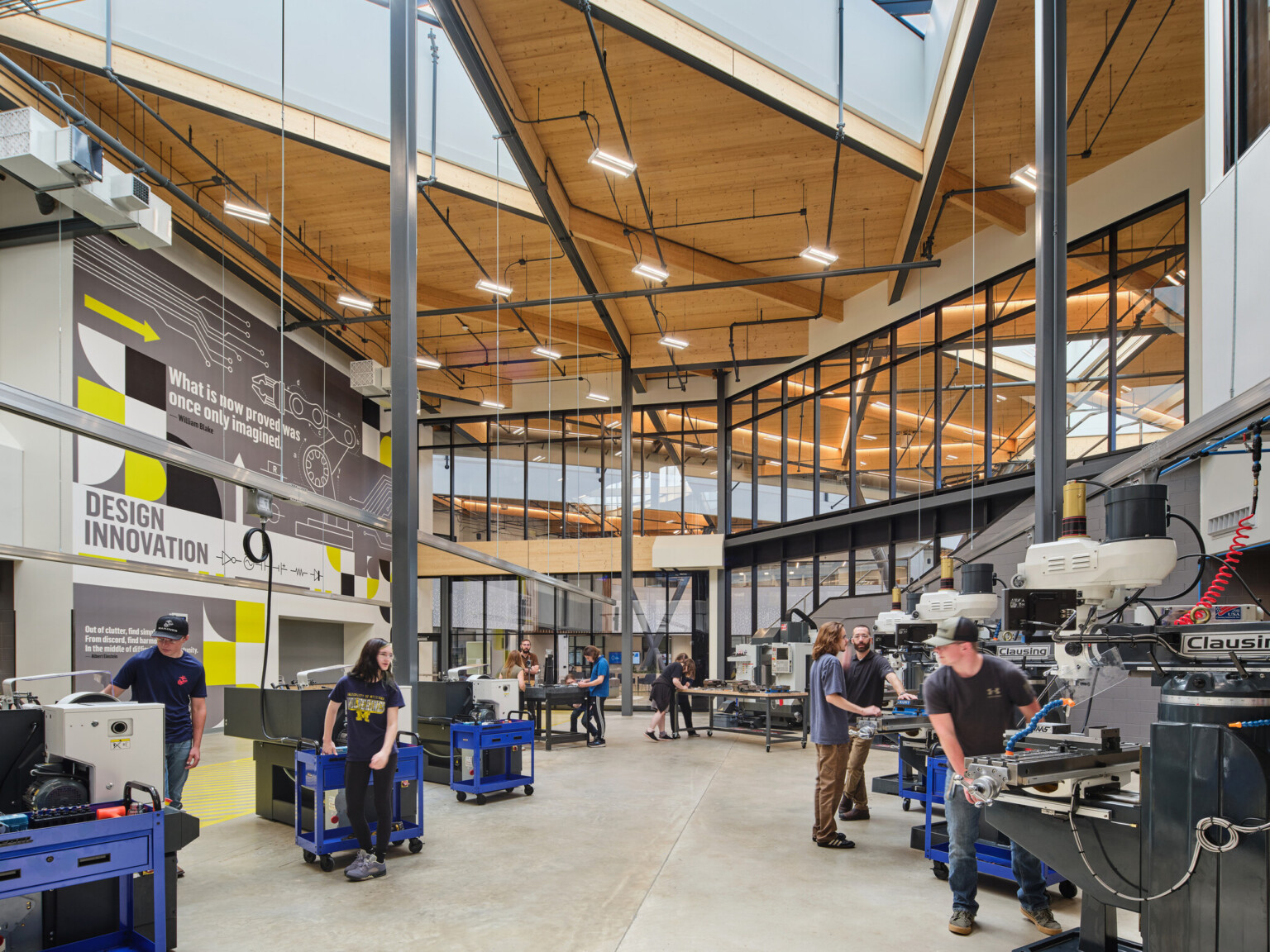 Technical classroom within Kalamazoo RESA career technical education building featuring exposed wood structure, natural materials, and biophilic design elements; students working at stations in a large double height space