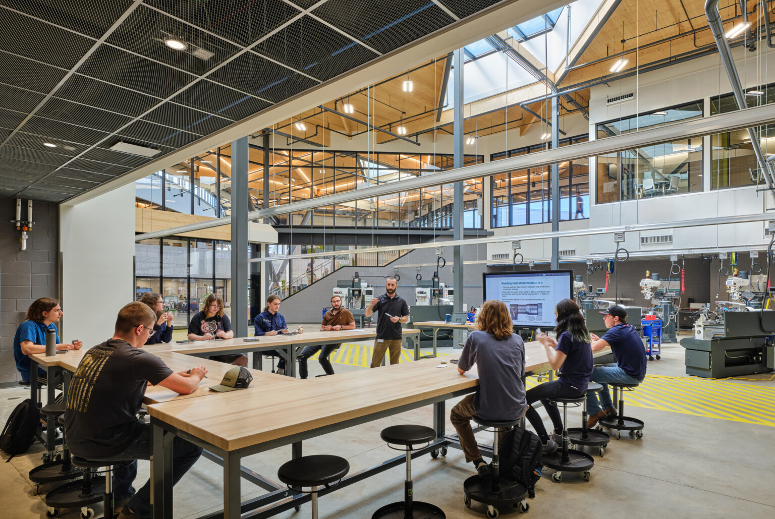 Technical classroom within Kalamazoo RESA career technical education building featuring exposed wood structure, natural materials, and biophilic design elements; students working at stations in a large double height space
