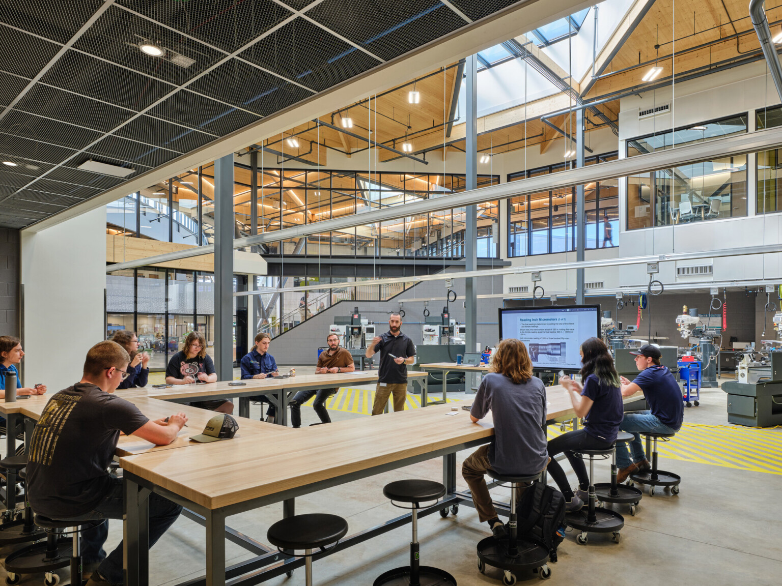 Technical classroom within Kalamazoo RESA career technical education building featuring exposed wood structure, natural materials, and biophilic design elements; students working at stations in a large double height space