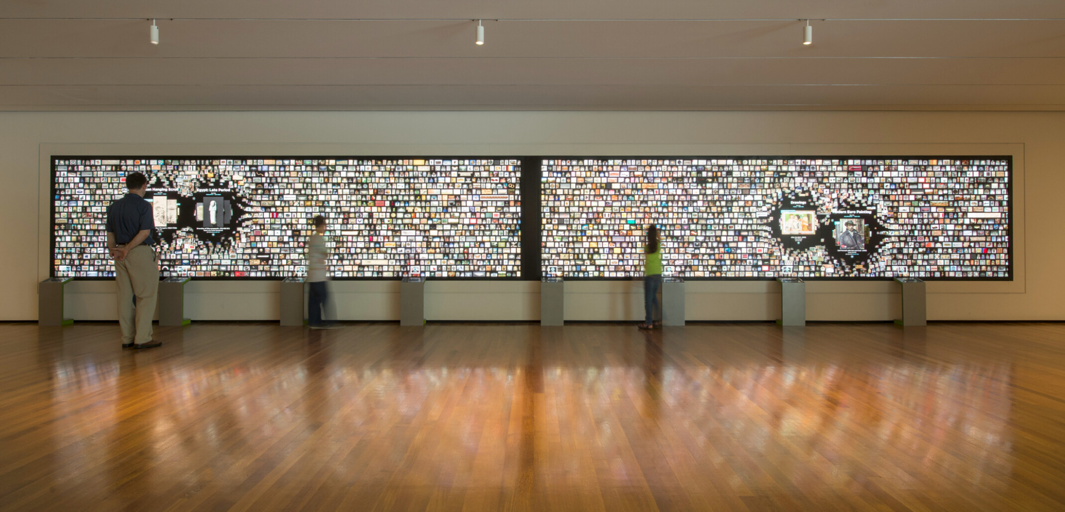 media exhibit in art museum comprised of two 8k screens combined displaying media, overhead spotlights maximize the focus on the screen, gleaming hardwood floors, high-ceilings, wide-open space