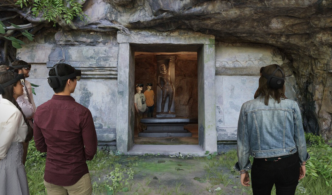 People using virtual realty VR headset at entry of Revealing Krishna exhibit, stone facade of ancient cave temple reproduction