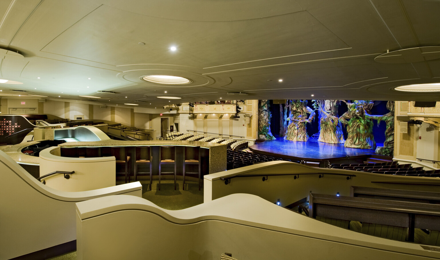 theater with varying types of seating. multiple levels going down to stage illuminated with blue lights