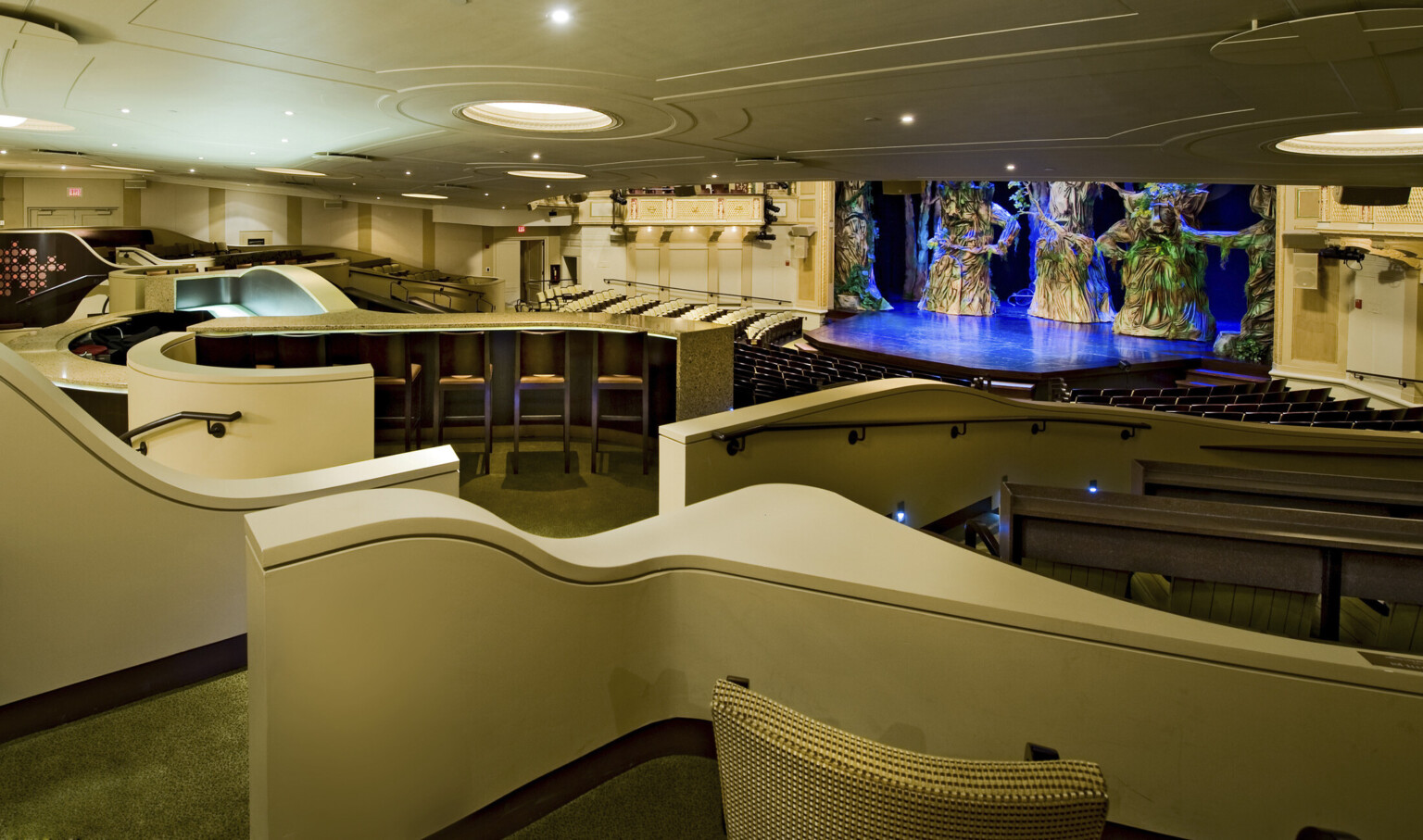 theater with varying types of seating. multiple levels going down to stage illuminated with blue lights