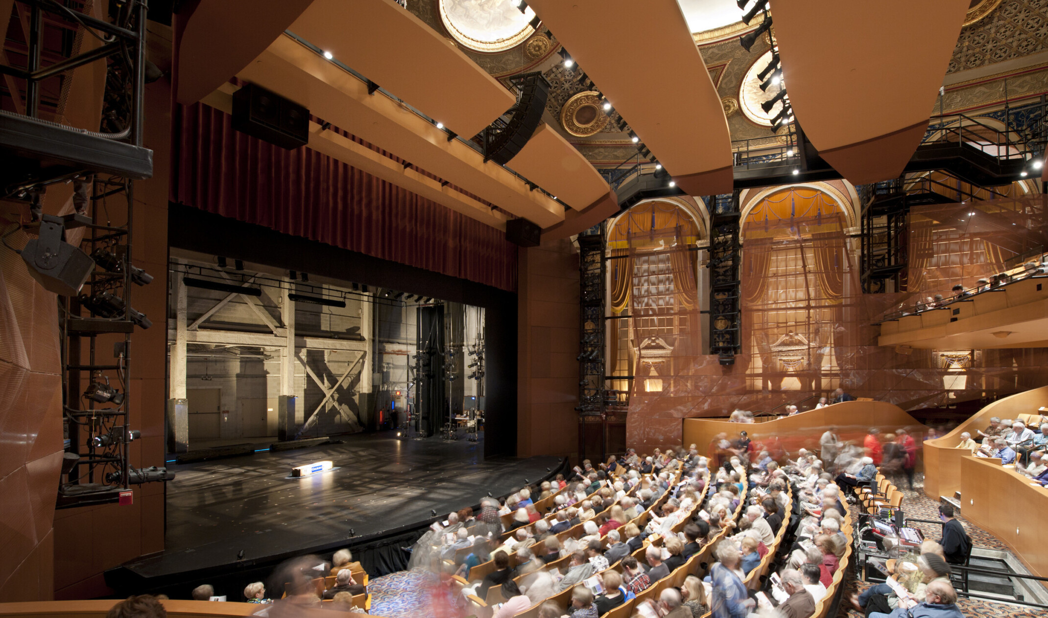 Theater seen from the side over the audience with large arch shaped windows. The stage is empty and stage right can be seen