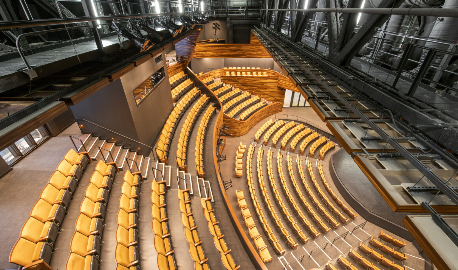 View from above the balcony looking down, there are catwalks above the seating and in the balcony is a grey room with window