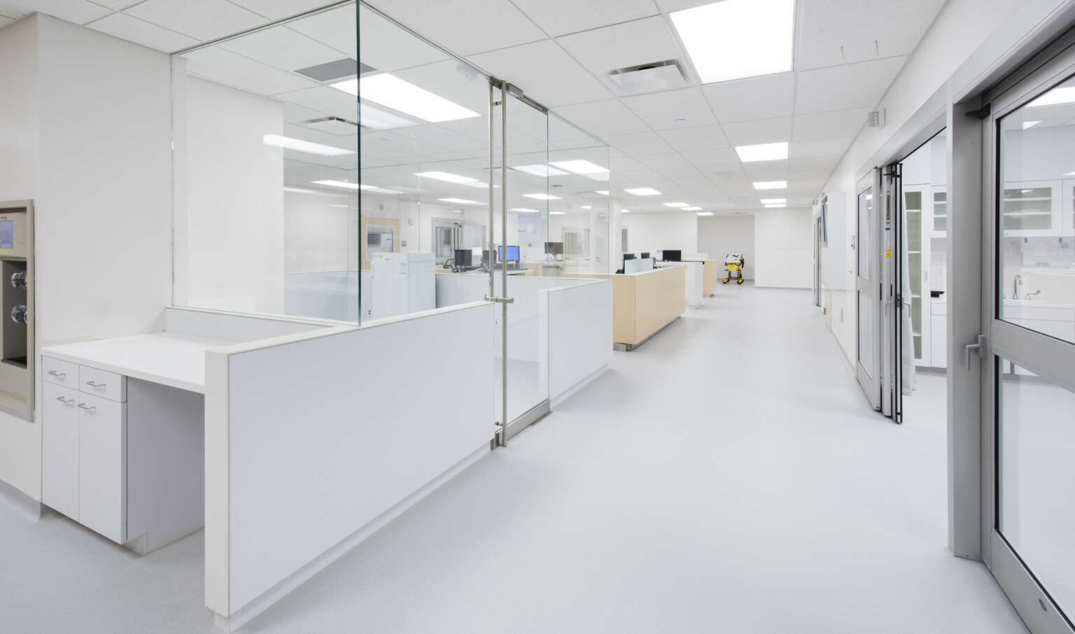 Bright white emergency room nurses stations opposite patient rooms have glass walls for visibility Bright white emergency room nurses stations opposite patient rooms have glass walls for visibility