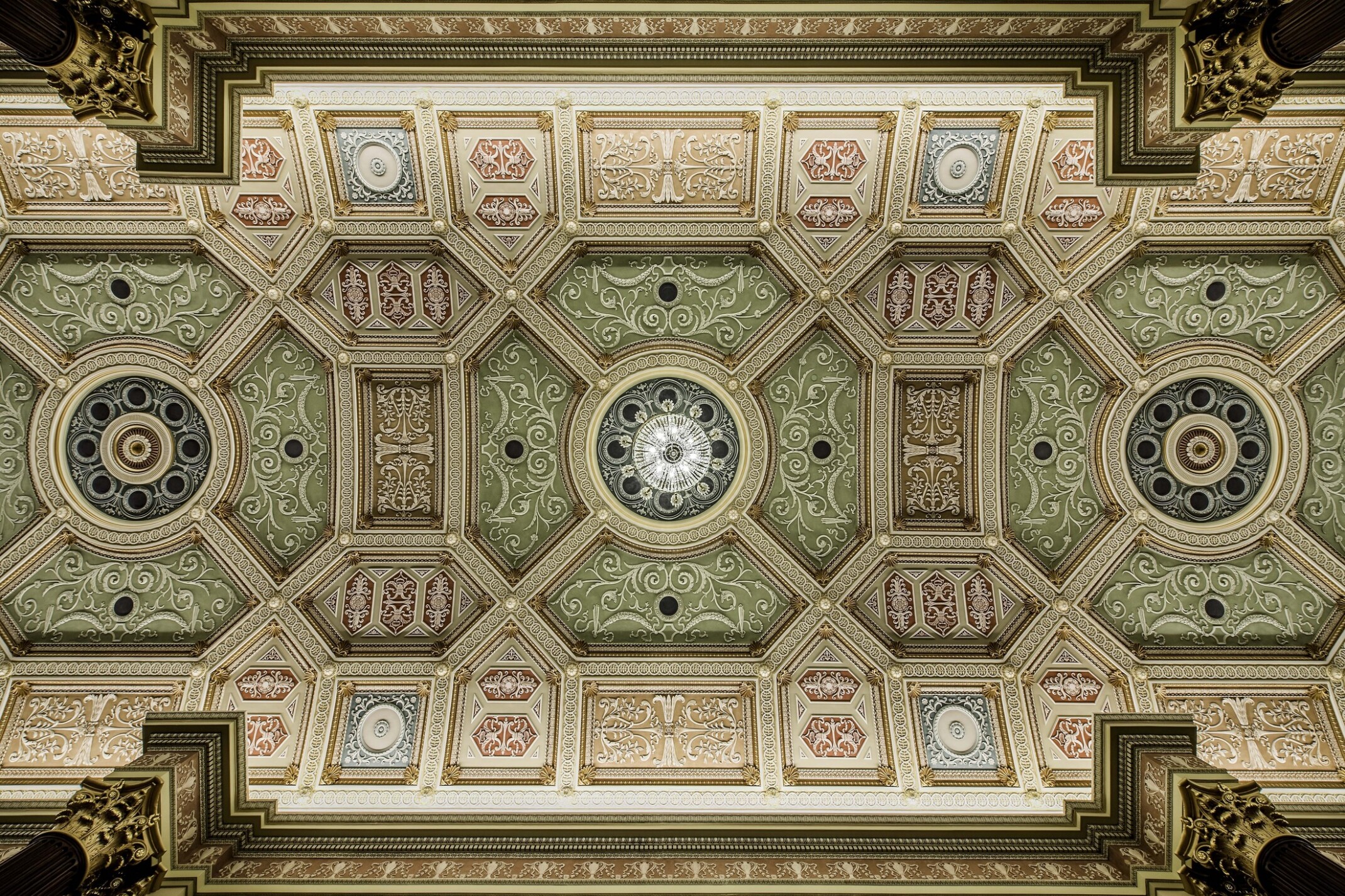 intricately designed ceiling with crown molding; green and light red coloring throughout