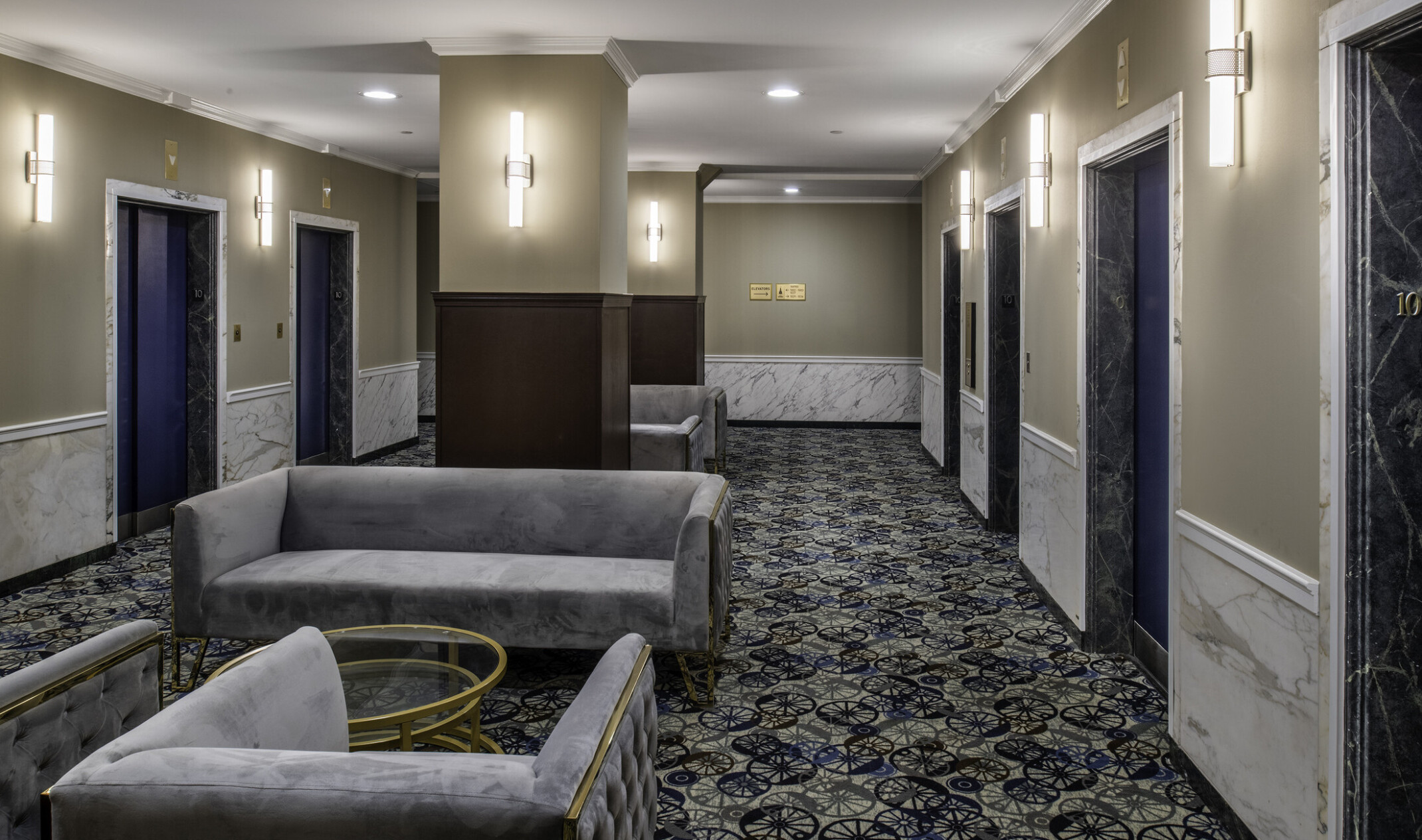 interior photo of a common space in an apartment building; patterned carpet with center area couches