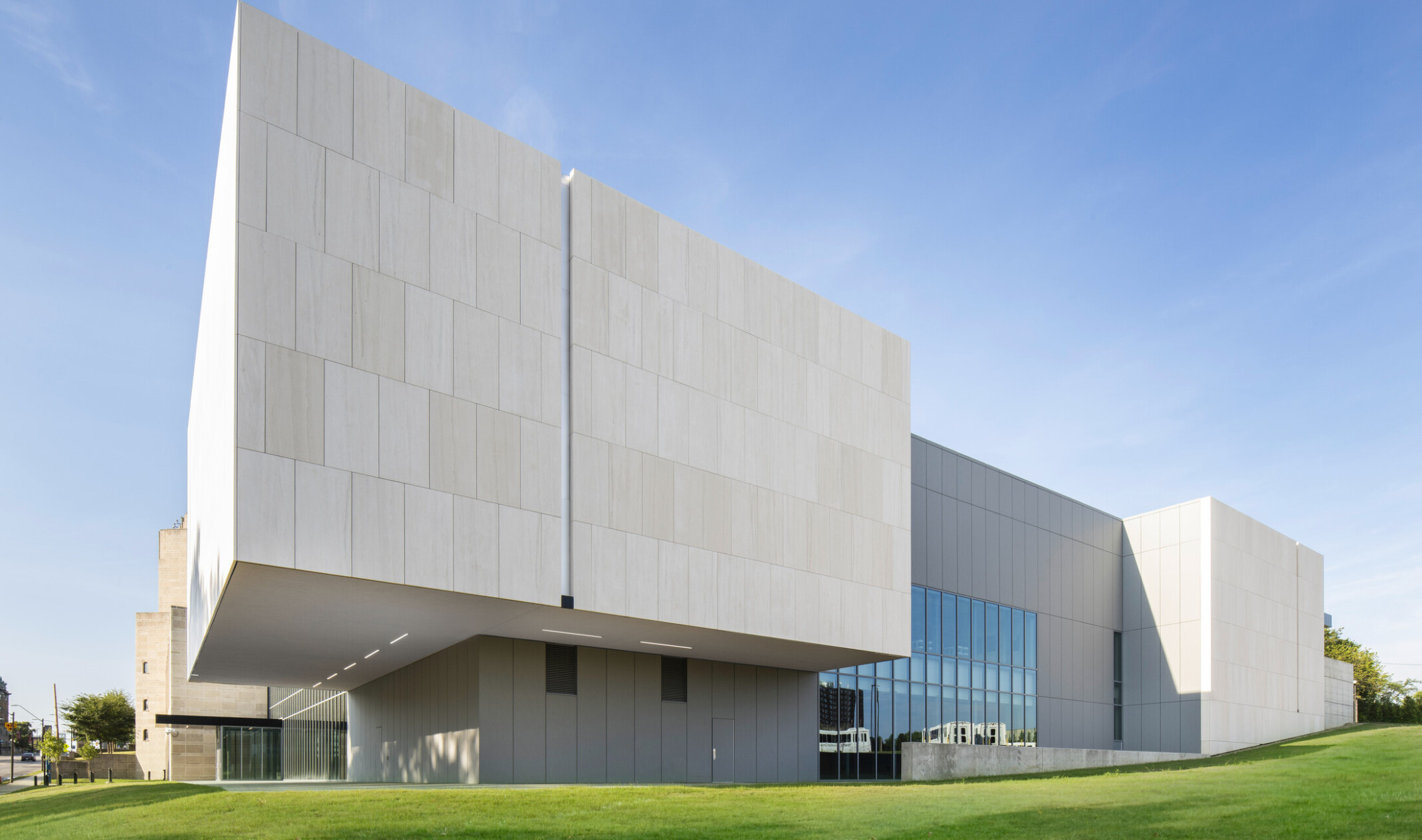 Exterior view of back corner of concrete building, built along a green grass hill