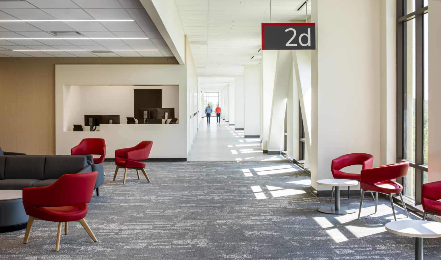 outpatient care facility uses modular pieces to replicate OSU's branding across several buildings, red modern chairs, grey patterned carpet, light beige walls & ceiling, light woods