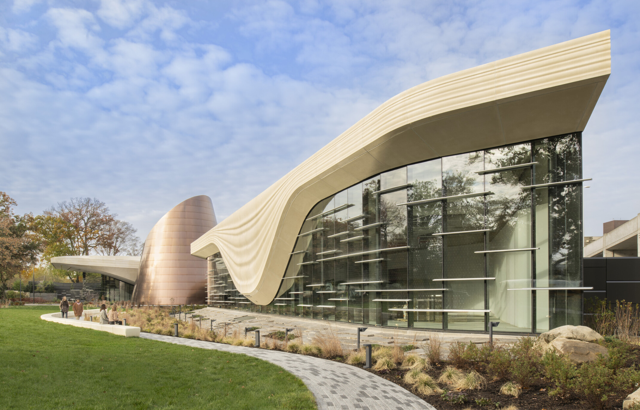Front facade of the Cleveland Museum of Natrual History; a geometric cream colored concrete structure outlines the large windows of the building to look like a glacier; backdropped by clear blue skies