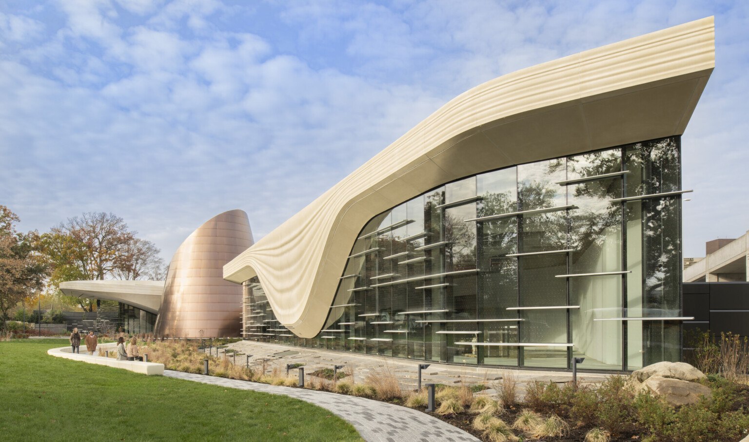 Front facade of the Cleveland Museum of Natrual History; a geometric cream colored concrete structure outlines the large windows of the building to look like a glacier; backdropped by clear blue skies