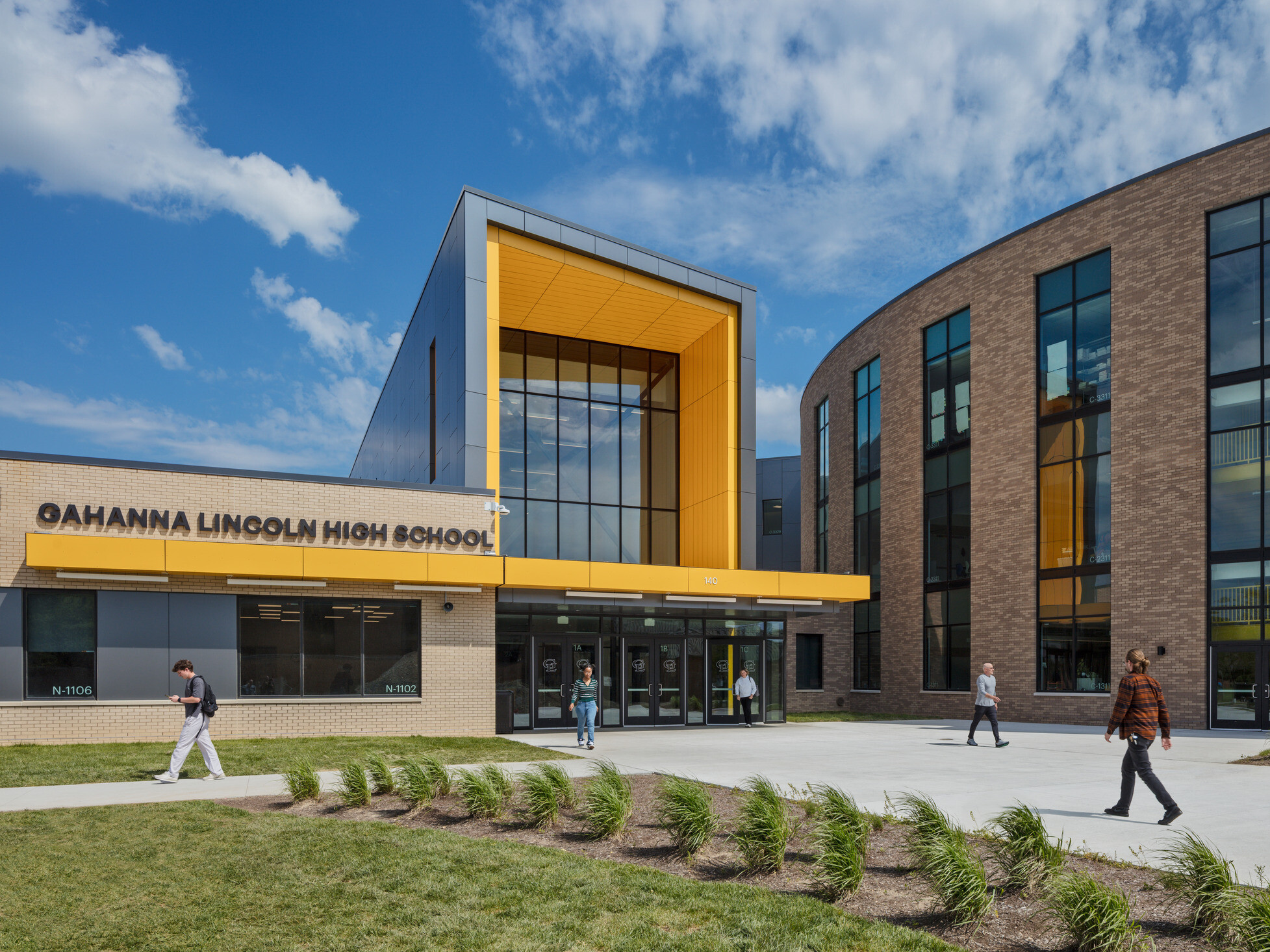 Front entrance to Lincoln High School. Landscaped sidewalk to 3 story building with covered entrance, round building to right