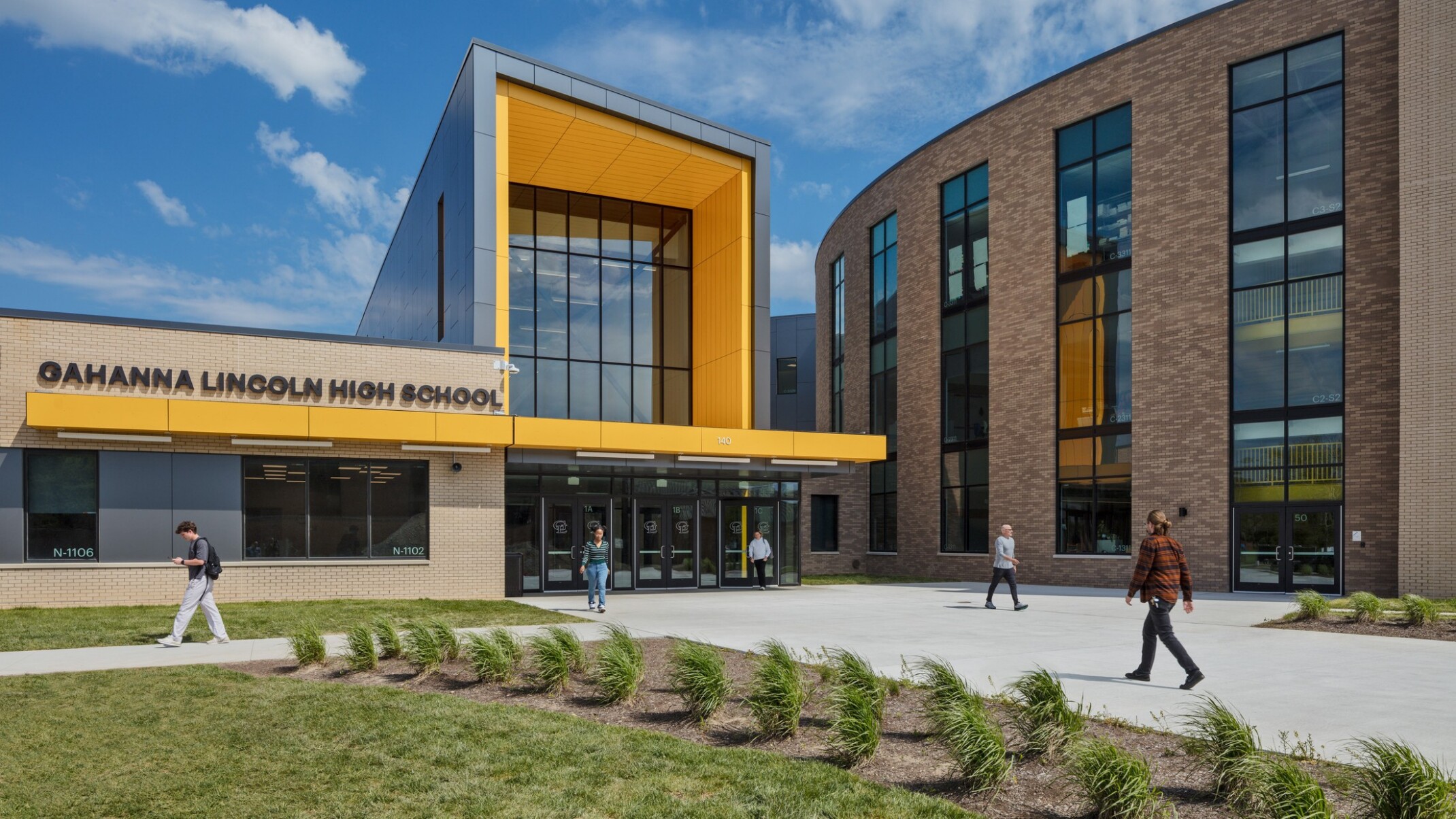 Front entrance to Lincoln High School. Landscaped sidewalk to 3 story building with covered entrance, round building to right