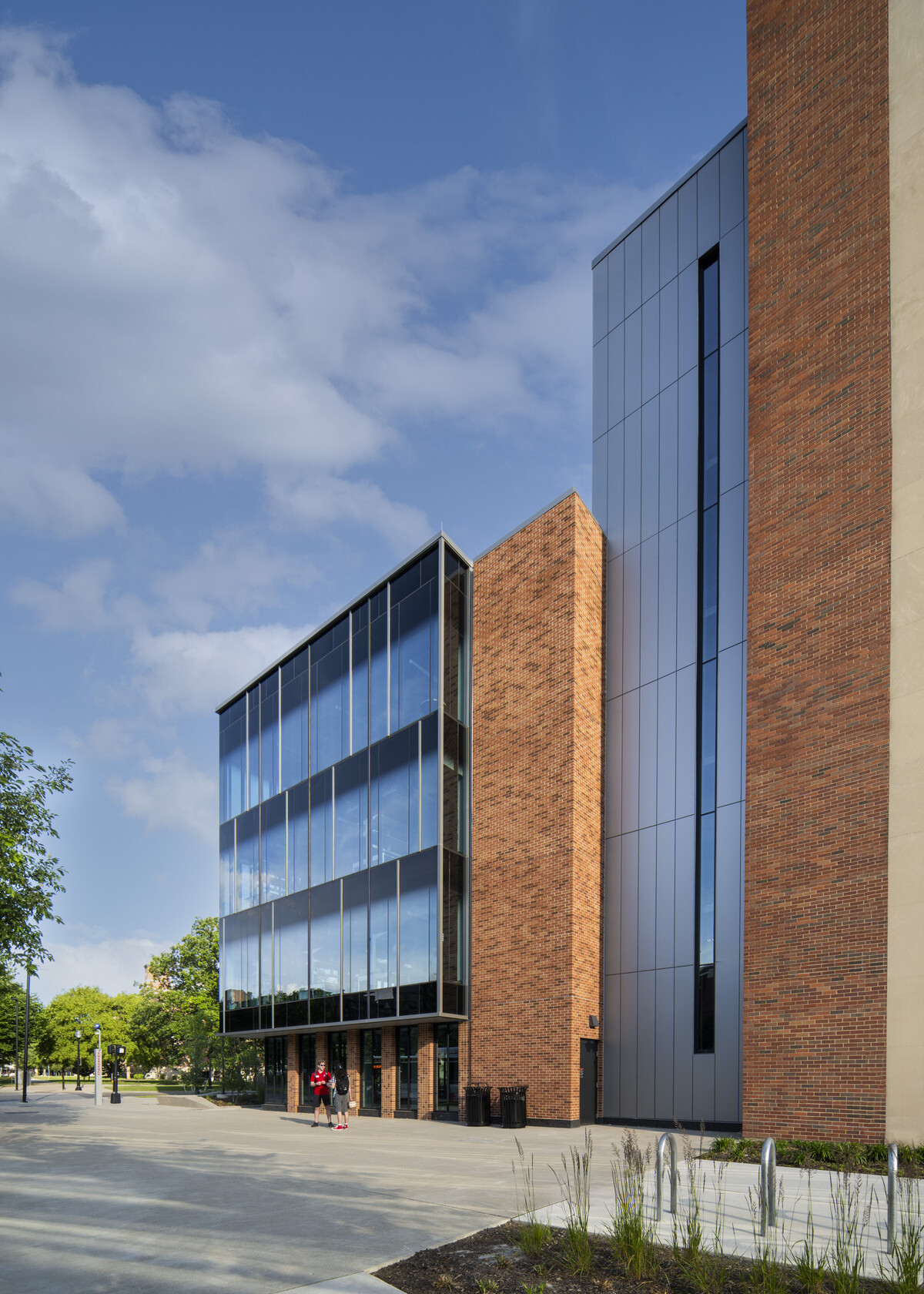 exterior of a modern building with a multi-facade treatment; entrance with floor to ceiling windows