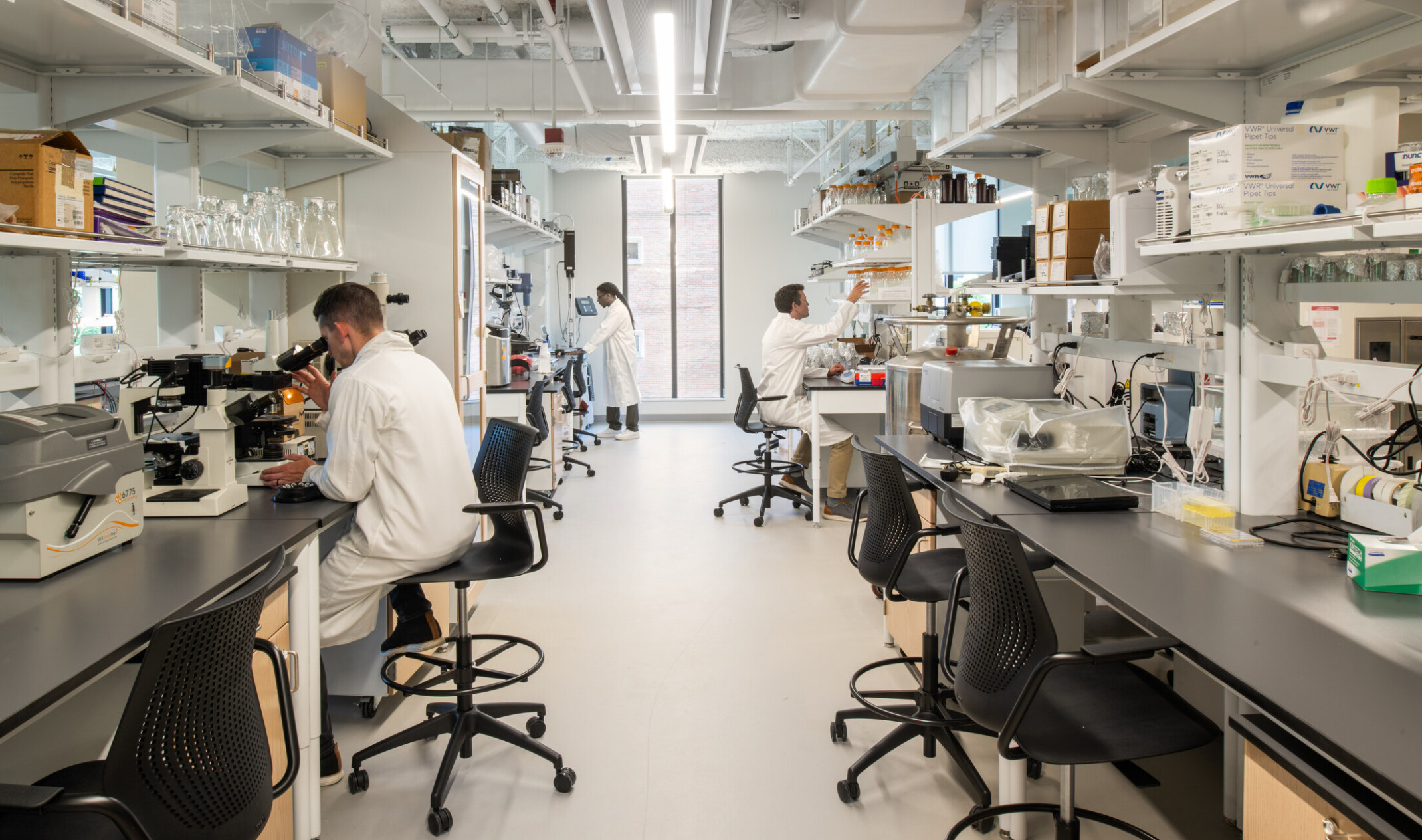 lab space; looking down a row of stations with technical equipment and students working on either counter