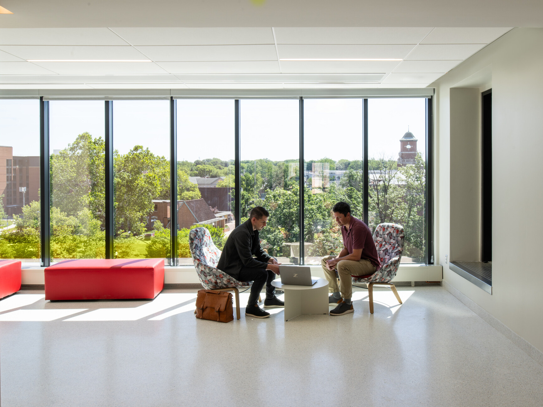 modern community space in a science building; comfortable modular, sitting space looks into nature/campus floor to ceiling glass