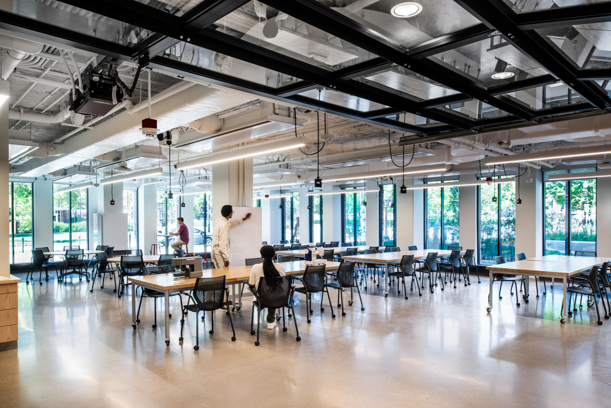 modern, naturally lit classroom with rows of tables facing a large TV and lecture stand