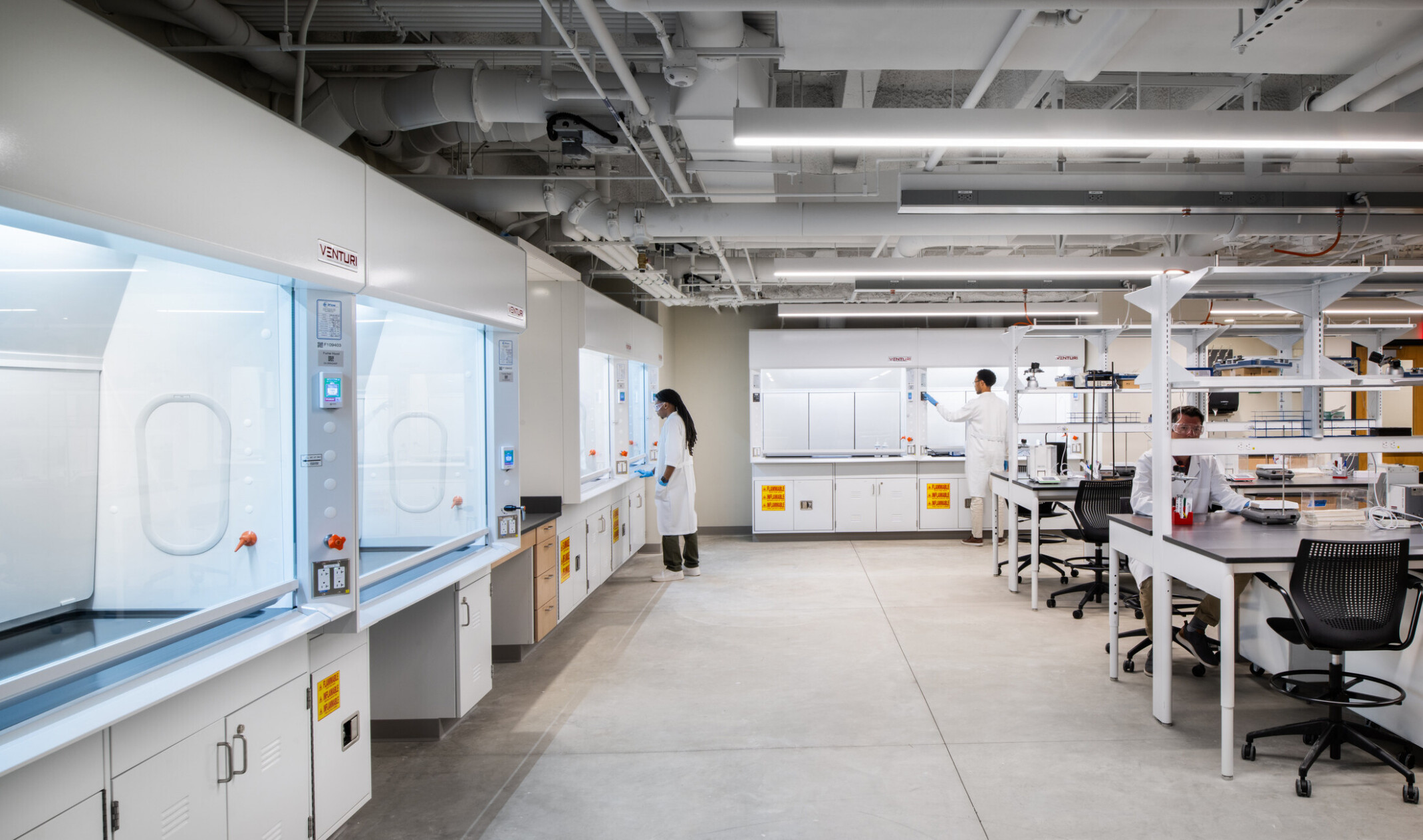 lab space; looking down a row of stations with technical equipment and students working on either counter
