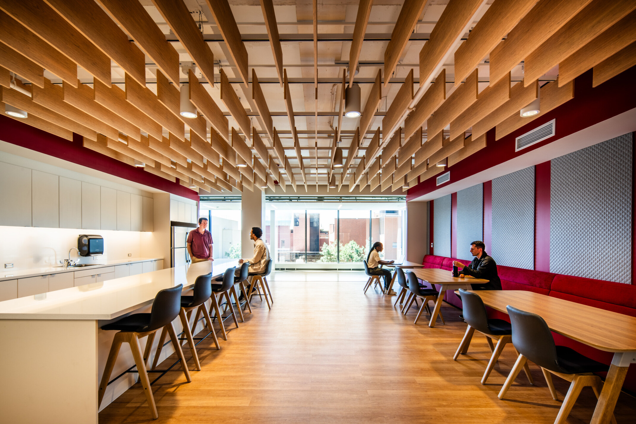 modern community space in a science building; bar seating space looks into an open concept lab behind floor to ceiling glass