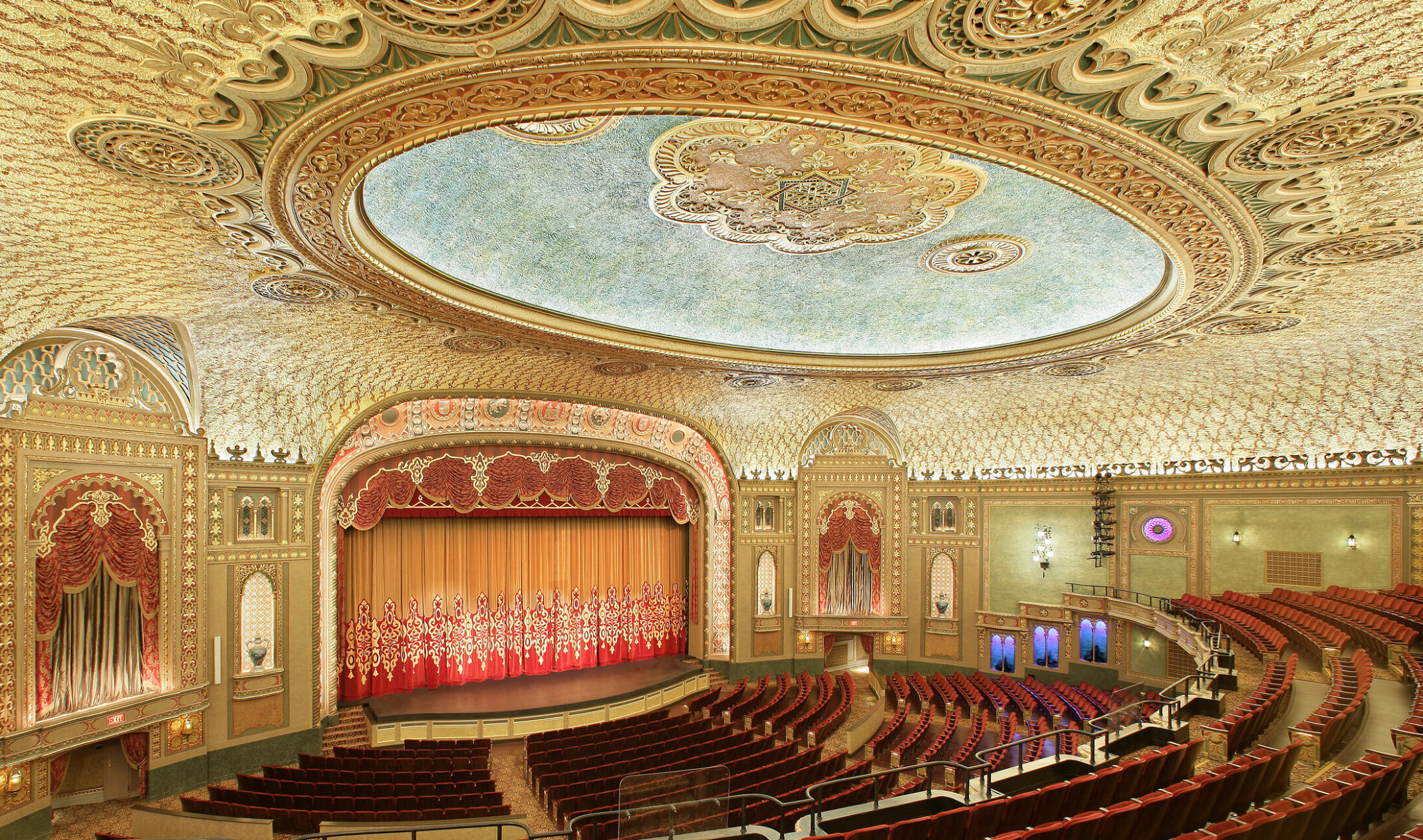 Interior of the Tennessee Theater, seen from the balcony looking to stage, ornate golden-patterned ceiling with round, recessed detail, dark red theatre seating