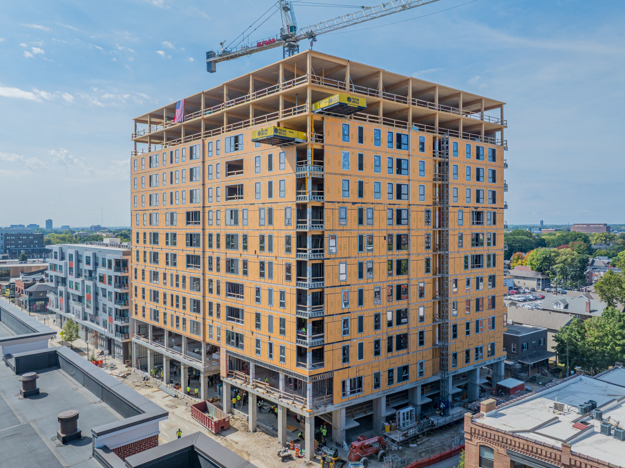 mass timber construction building with frame exposed and crane operating in the background