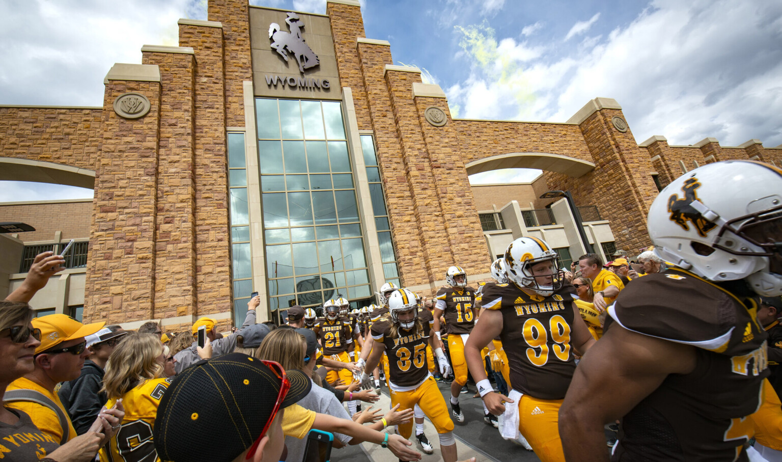 Entrance to stone building with central double height windows under mascot logo, framed by stepped stone facade and archways