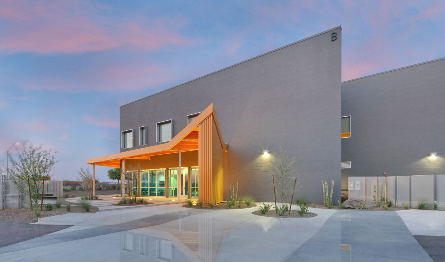West-MEC Central Campus, a grey angular building with yellow pointed canopy wrapping down right side of glass entrance West-MEC Central Campus, a grey angular building with yellow pointed canopy wrapping down right side of glass entrance