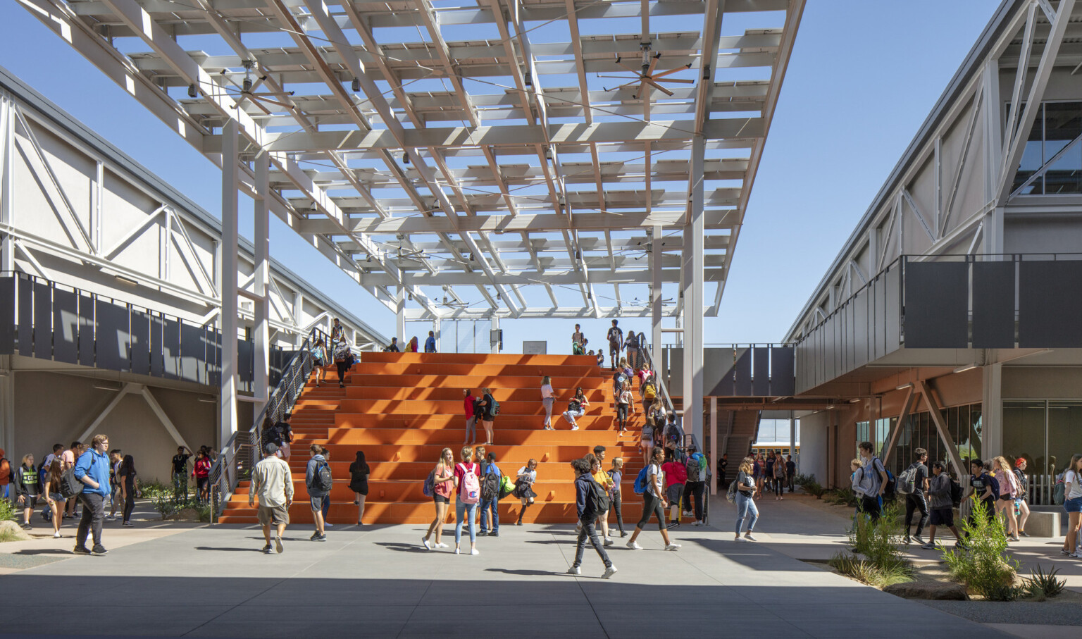 Looking out to students on orange bleacher steps partially cover by a solar canopy