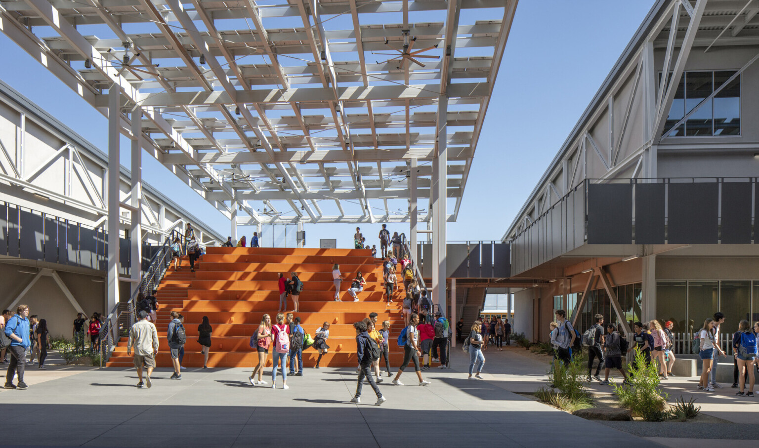 Looking out to students on orange bleacher steps partially cover by a solar canopy