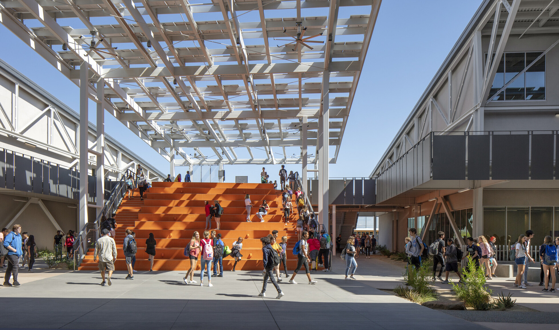Looking out to students on orange bleacher steps partially cover by a solar canopy