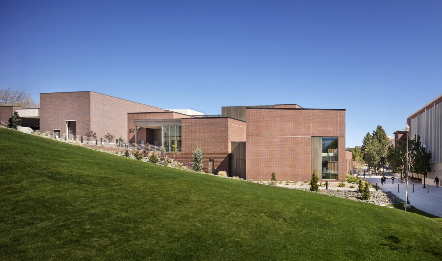exterior view of the south elevation of the site with green grass covered hill in the forefront