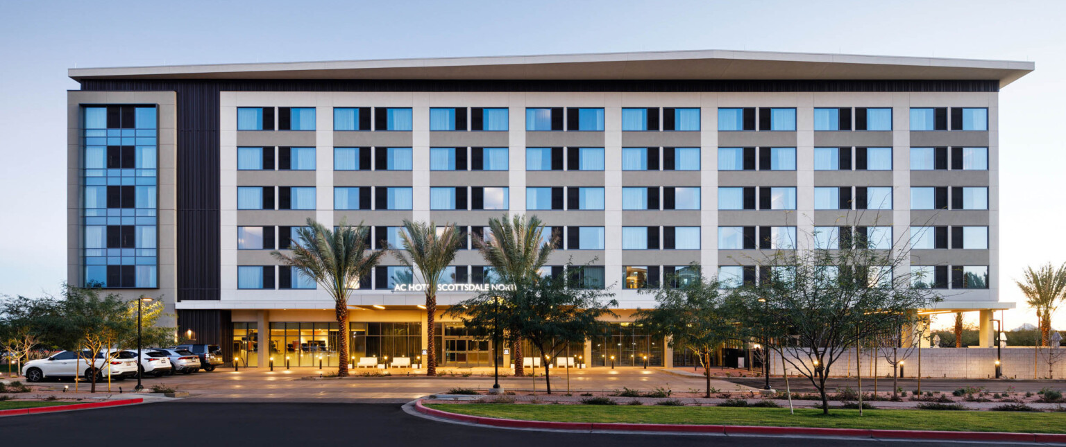 exterior design of a hotel with blue windows, white vertical panels, and palm trees out front