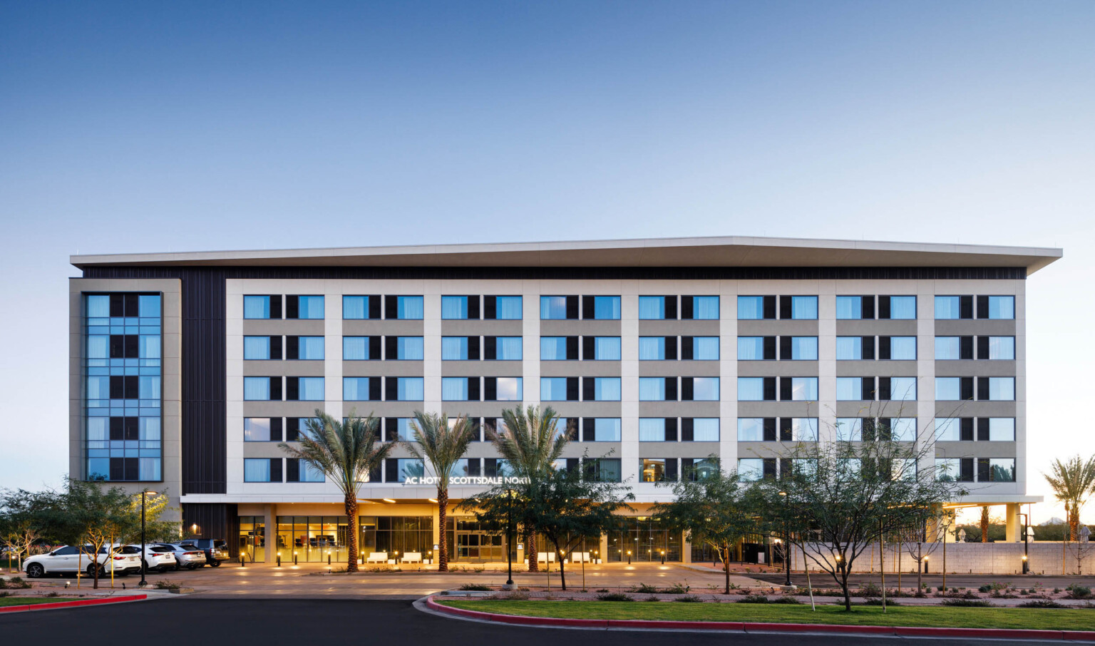 exterior design of a hotel with blue windows, white vertical panels, and palm trees out front
