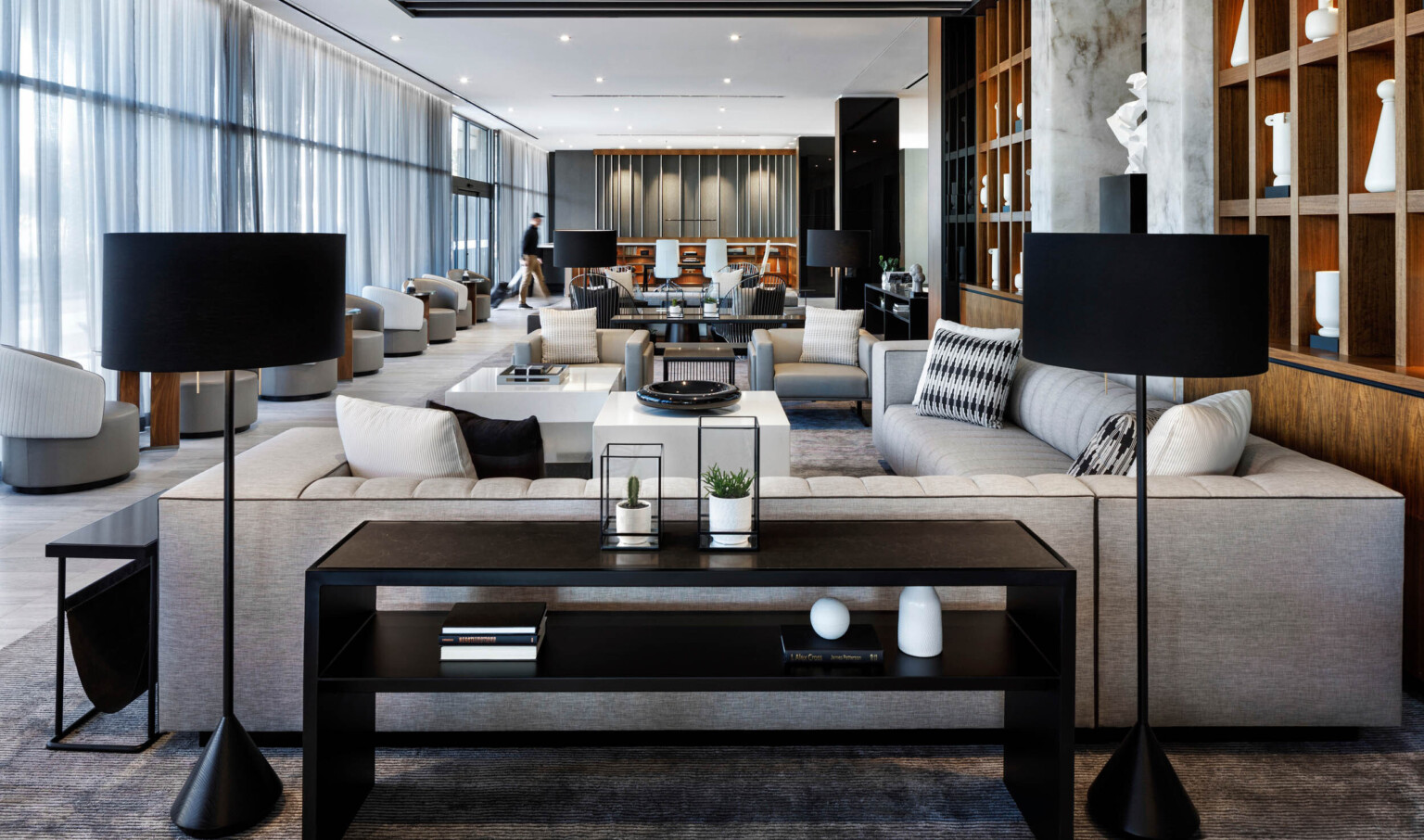 monochromatic hotel lobby with black floor lamps, black table and gray sofa