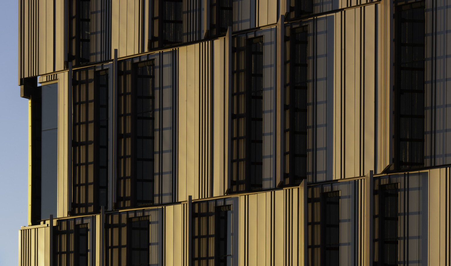 side view of courthouse with serrated sunscreen facade, a pattern of yellow panels peaking between. Floor to ceiling windows side view of courthouse with serrated sunscreen facade, a pattern of yellow panels peaking between. Floor to ceiling windows