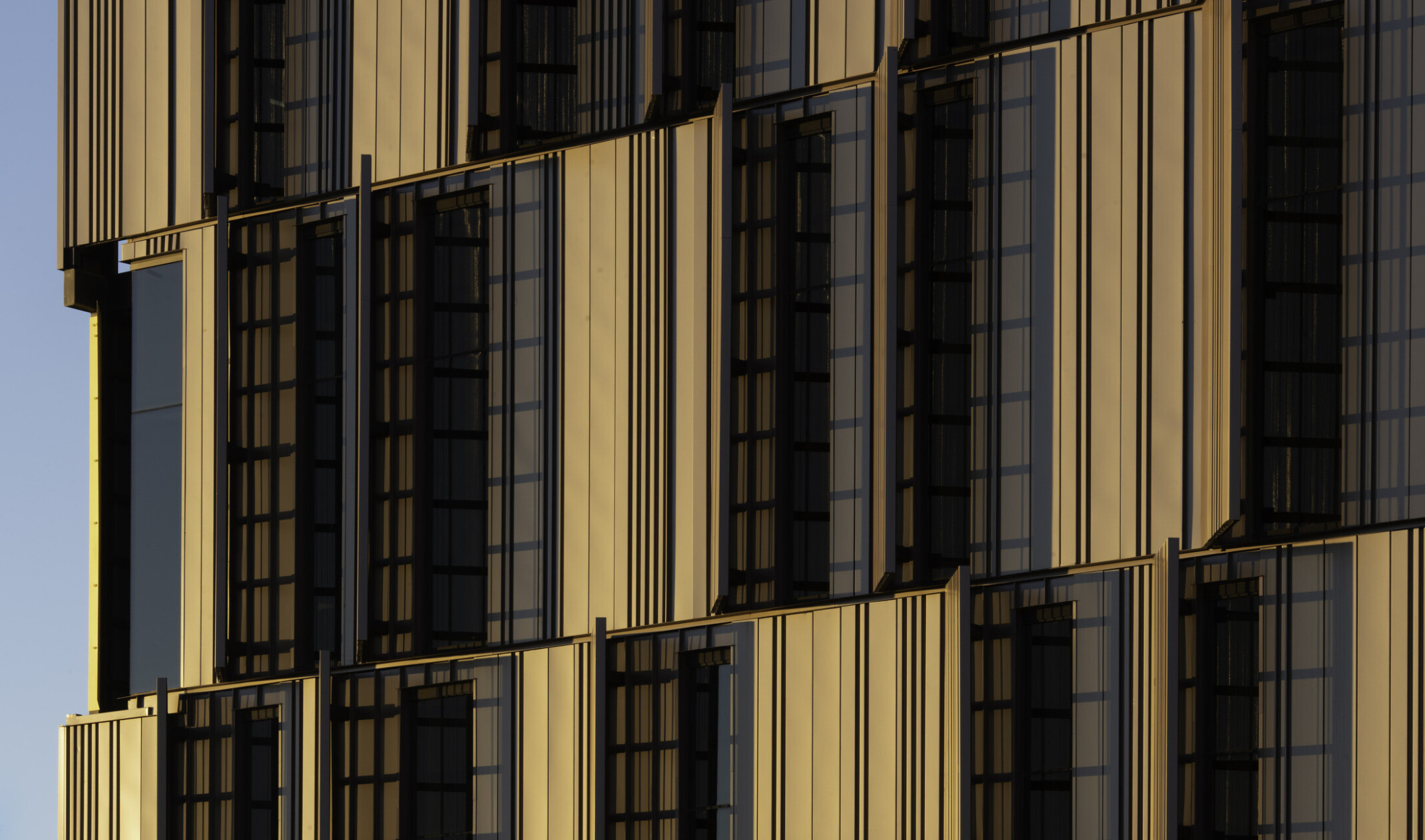 side view of courthouse with serrated sunscreen facade, a pattern of yellow panels peaking between. Floor to ceiling windows