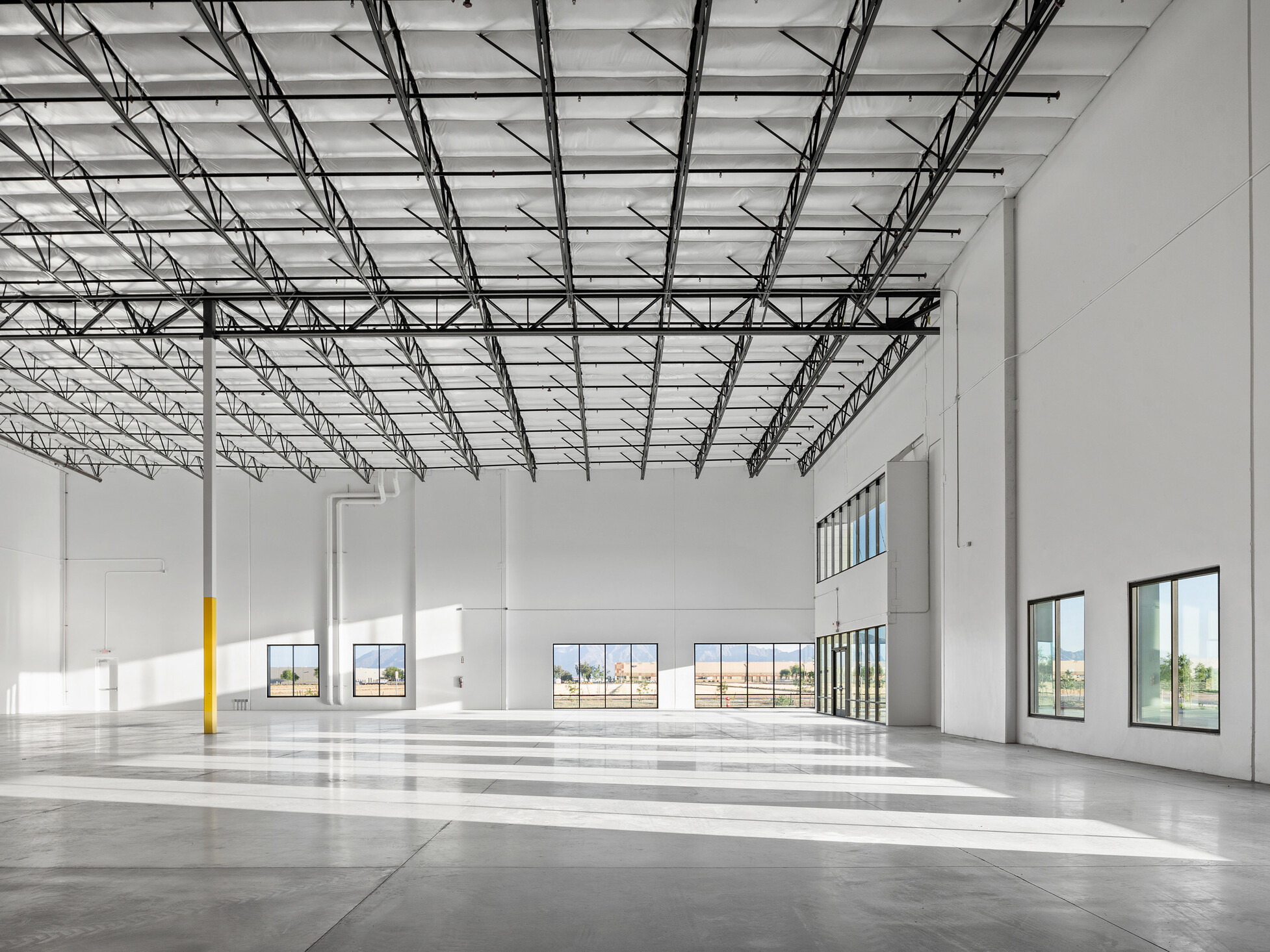 Avondale Commerce Park speculative office area; double-height window system at entry flooding interior with natural light; soaring ceiling height accommodating future two-story office build-out or single-story with generous ceiling height; open unfinished interior ready for tenant improvement