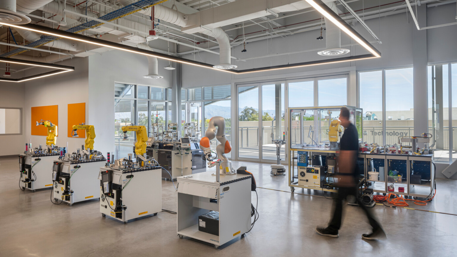 Classroom with large windows filled with four stations of mechanical arms and other equipment Classroom with large windows filled with four stations of mechanical arms and other equipment