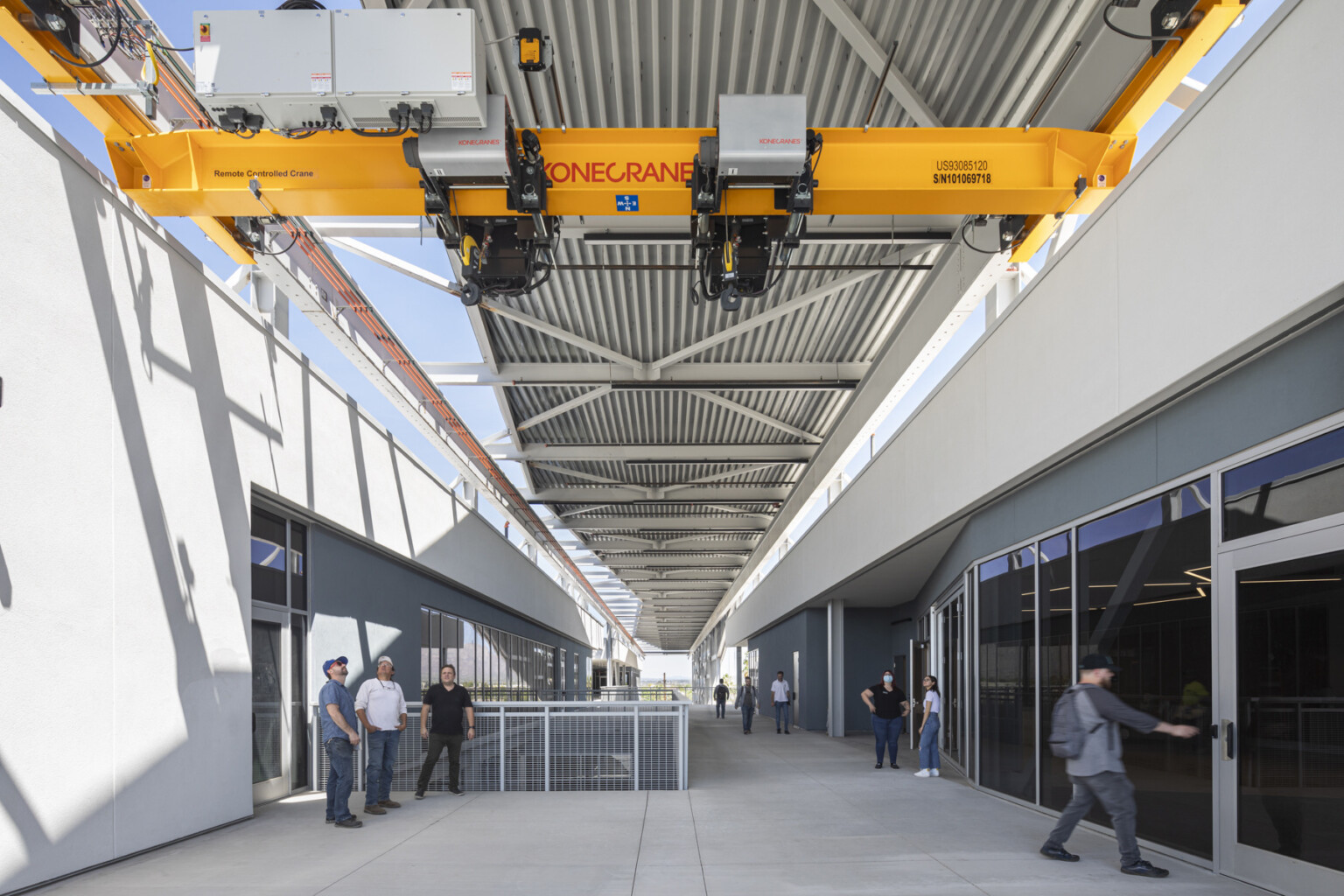 Crane extends from 2nd floor of building to place items on loading truck, right. Exposed hallways partially shaded by screen