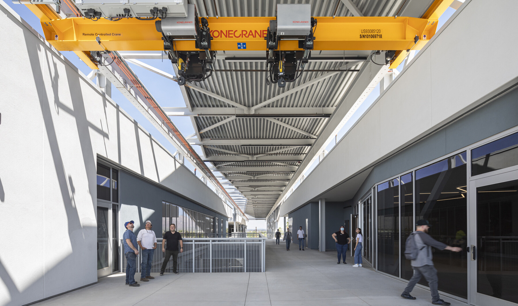 Crane extends from 2nd floor of building to place items on loading truck, right. Exposed hallways partially shaded by screen