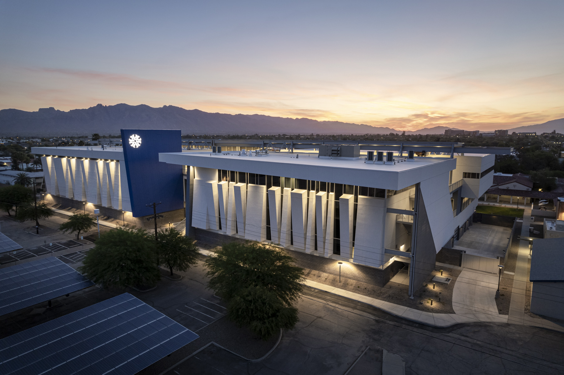 Pima Community College Center of Excellence for Applied Technology building exterior with angled outcrops and glass façade, dramatic lighting after dark