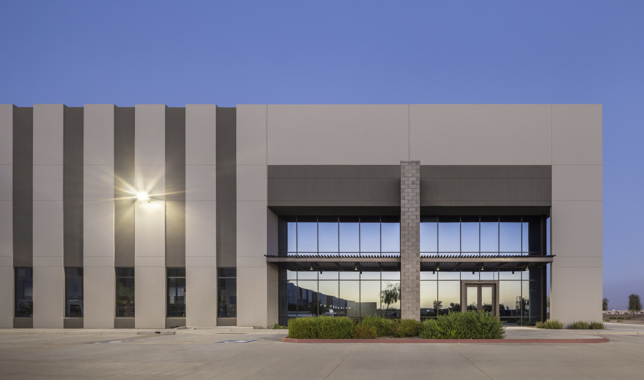 Straight-on view of a GO | 99 South building entrance with textured concrete block detailing, steel accents, and storefront glazing under a canopied entry