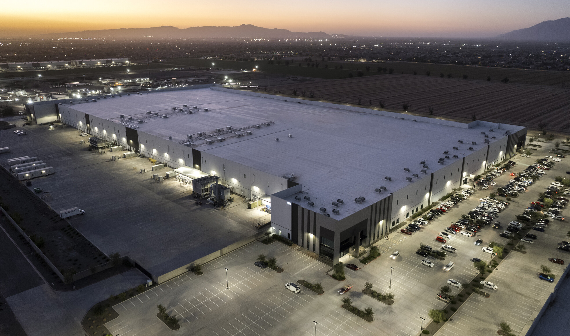 Aerial view of GO|99 South's three tilt-up concrete logistics buildings at dusk, softly illuminated with the West Valley's mountains in the background.