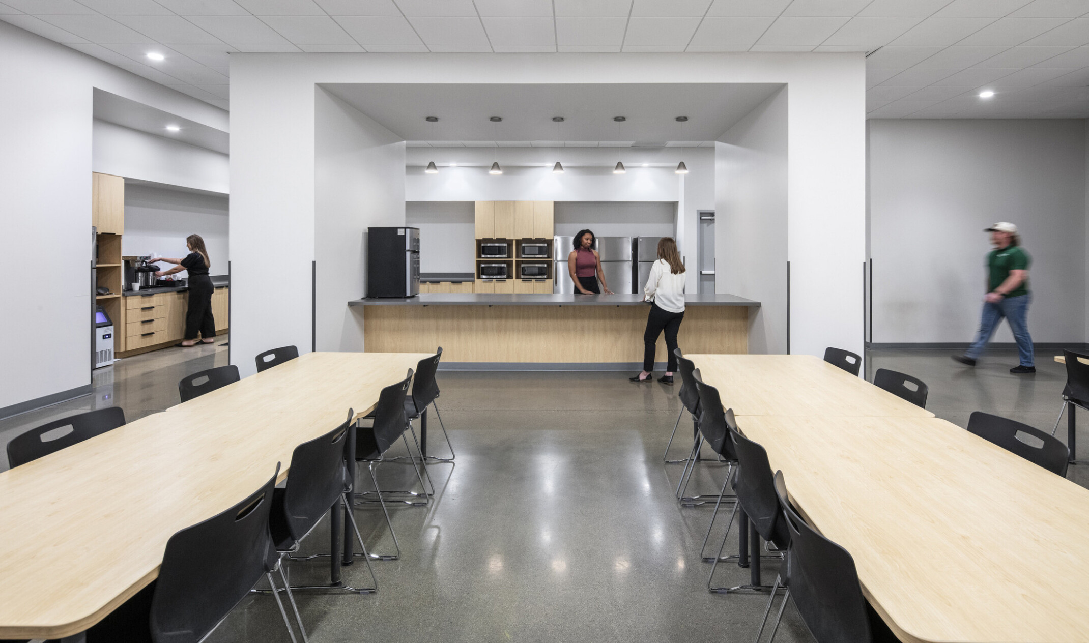 Wildeck breakroom; long communal tables; multiple microwaves and refrigerators; light oak millwork and cabinetry with black accents